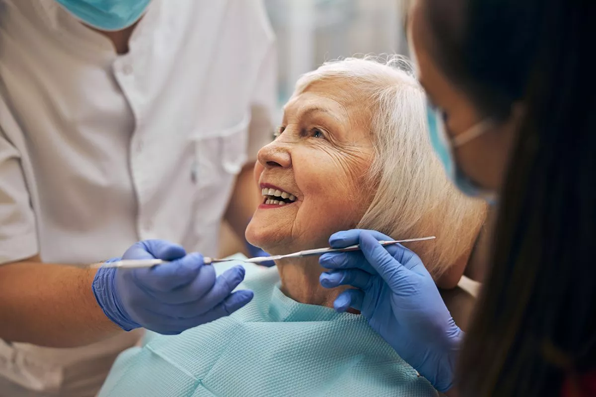 side-view-smiling-cheerful-female-patient-looking-doctor-whom-doing-cleaning-teeth-her