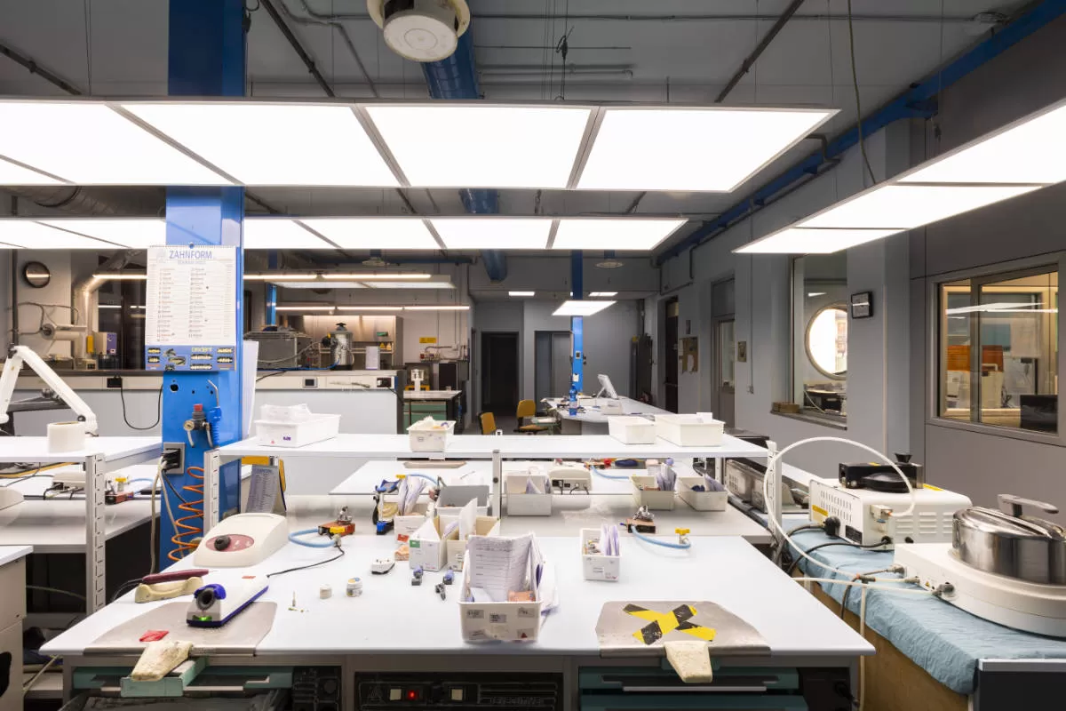 laboratorio odontotecnico magazzino con tavoli ingombri di strumenti e protesi
