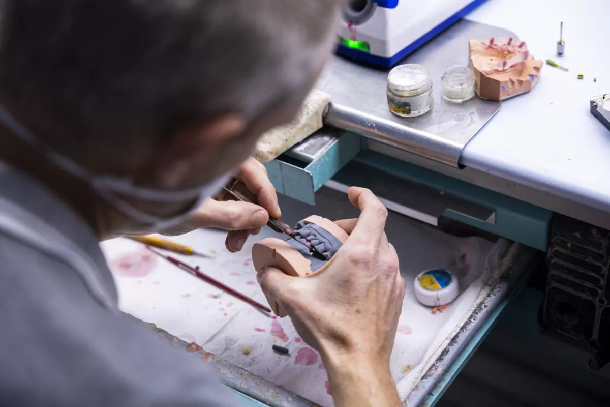 laboratorio odontotecnico tecnico rifinisce protesi con strumenti di precisione