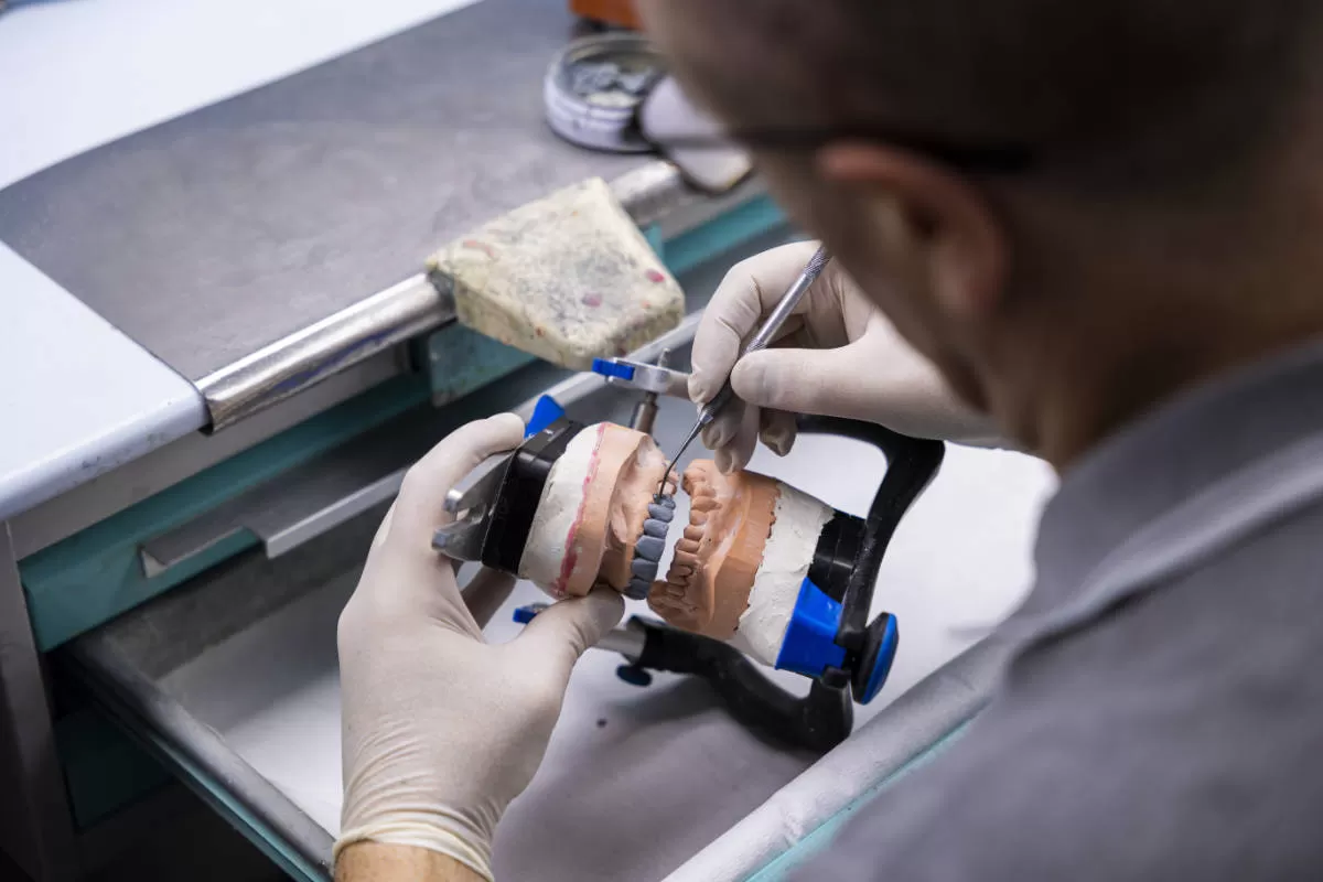 laboratorio odontotecnico tecnico al lavoro su protesi con strumenti di precisione